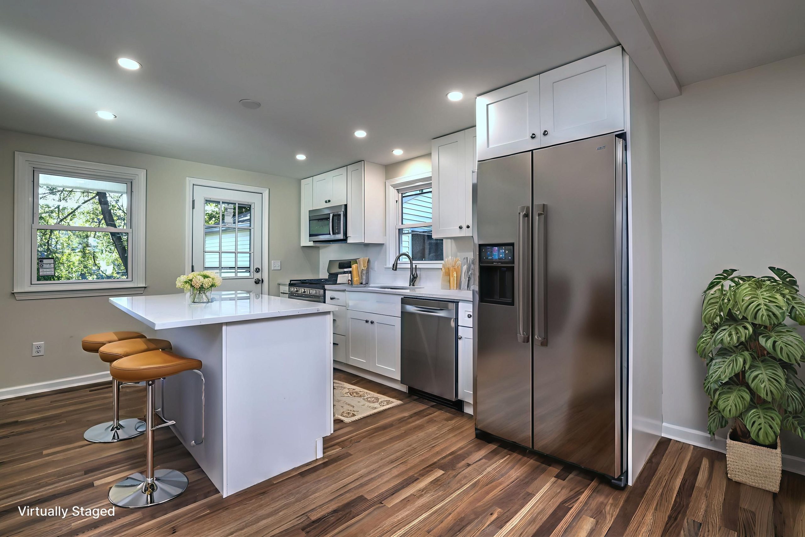 This modern kitchen features white shaker cabinetry, quartz countertops, stainless steel appliances, and a large center island with seating—perfect for casual meals or entertaining.