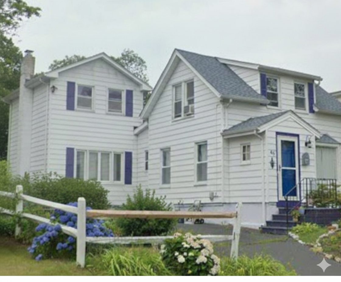 White two-story coastal home with blue shutters and front entry, located in New Haven’s Lighthouse neighborhood near the shoreline.